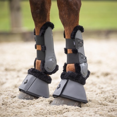 Perneiras e botas cinzentas com forro preto em patas de cavalo na areia
