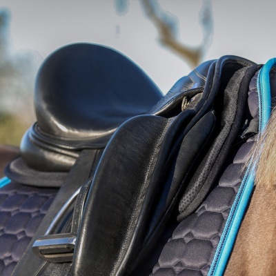 Sela de equitação preta em couro com stirrups metálicos e mantilla preta acolchoada com detalhe azul