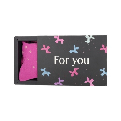 Caixa preta com texto For you e balões coloridos, contendo meias cor de rosa com bolinhas prateadas