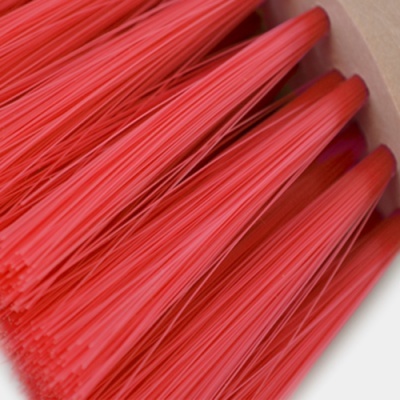 Pincel com cerdas vermelhas sintéticas e superfície branca ao fundo