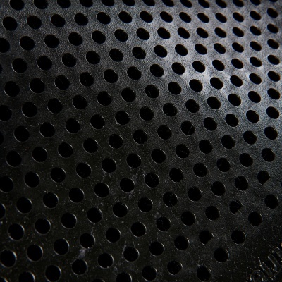 Superfície metálica preta com furos circulares em padrão uniforme