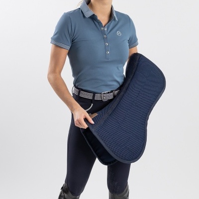 Mulher com polo azul e calças de equitação segurando manta azul escura acolchoada