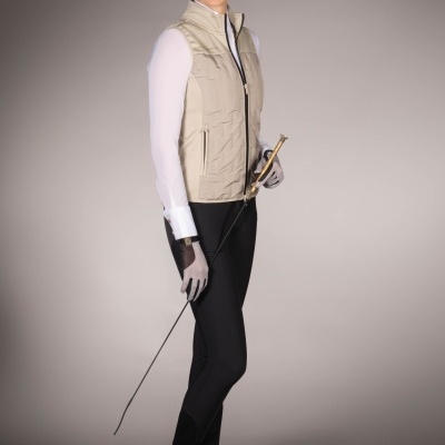 Mulher vestindo colete bege acolchoado e calças pretas, segurando bastão com pega dourada.