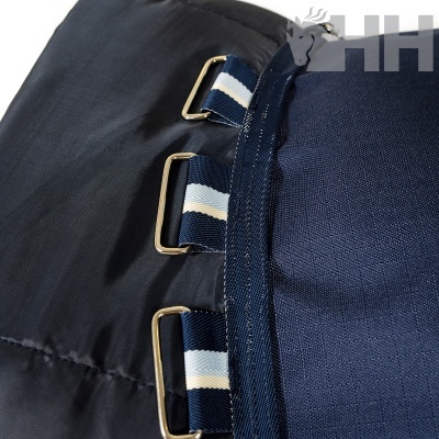 Detalhe de saco ou manta azul escuro com argolas metálicas e fitas listadas.