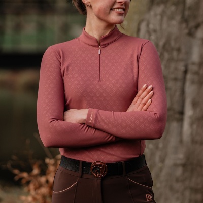 Sweatshirt feminina rosa com padrão de logótipos e calças castanhas ao ar livre