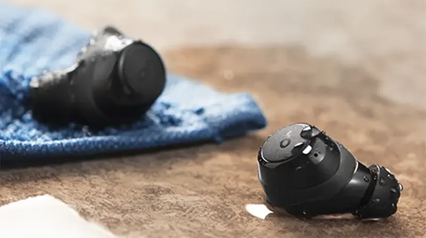 Análise aos auriculares bluetooth Soundcore Life A1 Auscultadores intra-auriculares pretos com gotas de água sobre superfície castanha