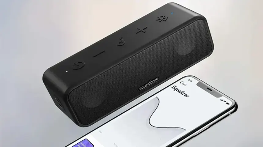 Coluna portátil preta Soundcore com smartphone ao lado
