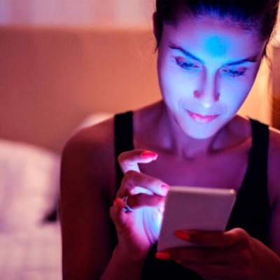 Mulher usando smartphone com luz azul num ambiente interior