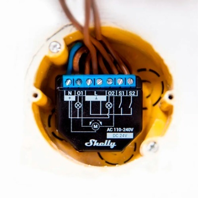 Dispositivo elétrico Shelly preto instalado em caixa amarela com fios conectados