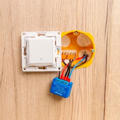 Interruptor elétrico com fios ligados numa caixa amarela embutida em parede de madeira