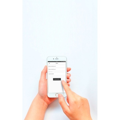 Smartphone branco com formulário de login na tela segurado por duas mãos.