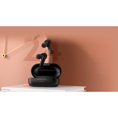 Auriculares sem fios pretos com estojo e livros sobre mesa em fundo castanho claro