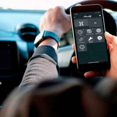 Pessoa ao volante de carro a usar smartphone com aplicação 'Drulik' no ecrã