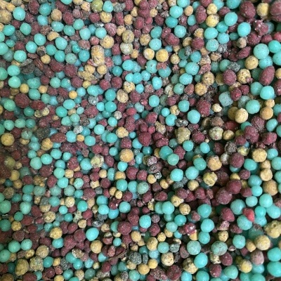 Pequenas esferas coloridas azul, castanhas e amarelas com textura granulada