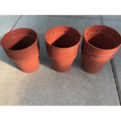 Potes de plástico castanho alaranjado empilhados no chão de cimento