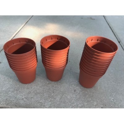 Três pilhas de vasos de plástico castanhos sobre chão de cimento