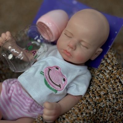 Boneca bebé realista com roupa branca e rosa a segurar biberão