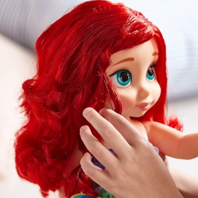 Boneca com cabelo vermelho e olhos azuis sendo segurada por uma mão.