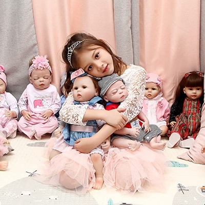 Menina rodeada por várias bonecas sentadas com roupas diversas em tons de rosa e branco.