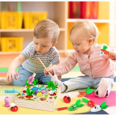 Dois bebés a jogar com brinquedo de pesca de madeira num tapete colorido