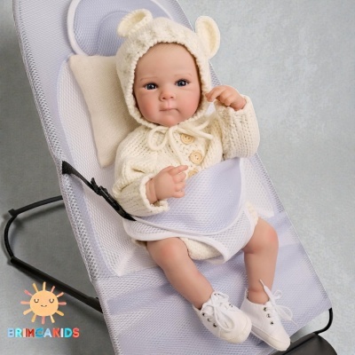 Boneca realista de bebé com roupa de malha creme e sapatilhas brancas sentada em cadeira de rede branca