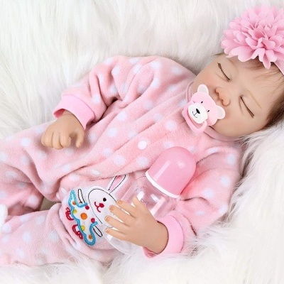 Bebé dormindo com pijama rosa de bolinhas e biberão