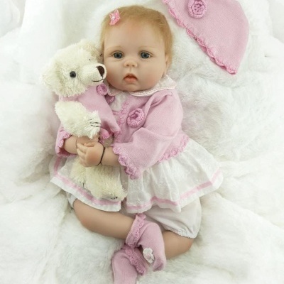 Boneca bebé realista com roupa rosa e ursinho de peluche branco