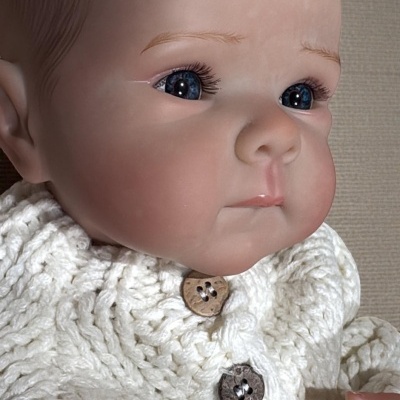 Boneca bebé realista de vinil com camisola branca de malha e botões de madeira