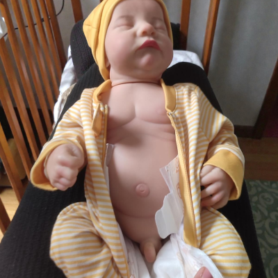 Boneco bebé realista com roupa às riscas amarelas e brancas