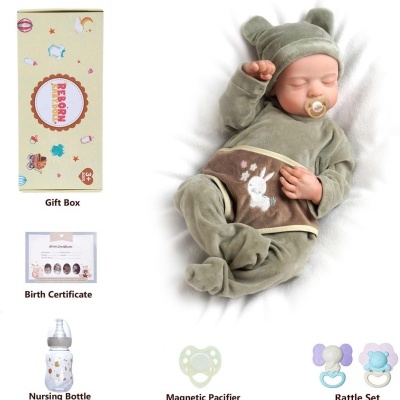 Boneca bebé realista com roupa verde e chupeta, acompanhada de garrafa e chocalhos