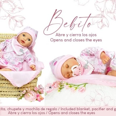 Boneca bebê vestida de rosa com manta, chupeta e mochila, em cesta de verga, fundo branco com flores e texto