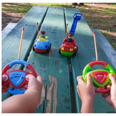 Carros de brinquedo telecomandados coloridos sobre mesa de madeira exterior