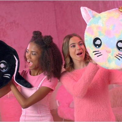 Dois sacos redondos com formas de animais segurados por duas mulheres num cenário rosa