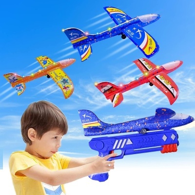 Criança brincando com lançador azul de aviões de brinquedo coloridos no céu