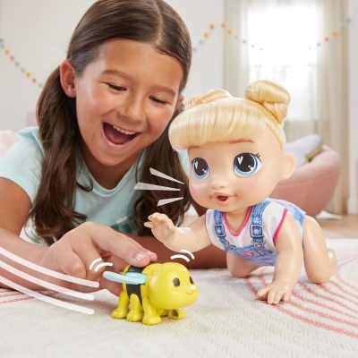 Boneca bebê loira e cão de brinquedo amarelo a brincar em tapete