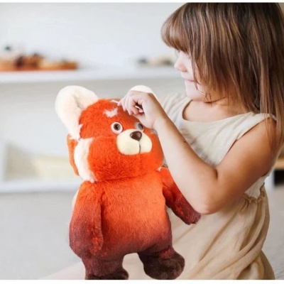 Menina com vestido bege a segurar peluche de panda vermelho no interior