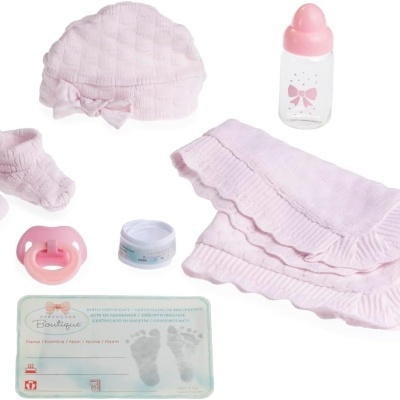 Conjunto de acessórios para boneca em tons de rosa claro com gorro, sapatinhos, manta, biberão, chupeta e cartão com pegadas