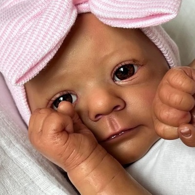Boneca realista com touca rosa e roupinha branca