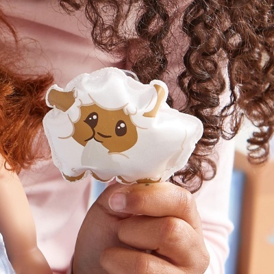 Boneco pequeno de pelúcia em forma de ovelha branca e castanha segurado por uma mão