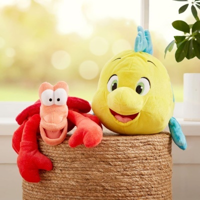 Peluches caranguejo vermelho e peixe amarelo com nadadeiras azuis numa cesta trançada