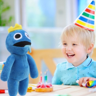 Boneco de pelúcia azul com coroa e criança a sorrir com chapéu de festa