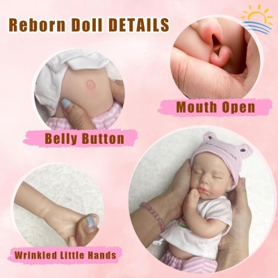 Detalhes da boneca reborn com boca aberta, botão da barriga, mãos enrugadas e chapéu rosa com orelhas.