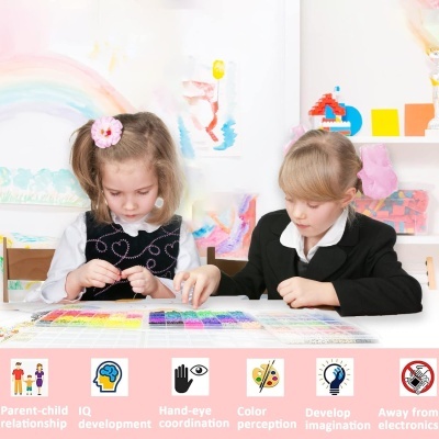 Duas meninas a brincar com pequenos objetos coloridos numa mesa branca numa sala infantil