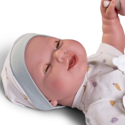 Boneca bebé vestida com roupa branca com padrão colorido e gorro
