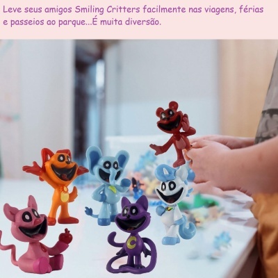 Figuras coloridas Smiling Critters de plástico com expressões alegres numa mesa branca e uma mão a segurá-las