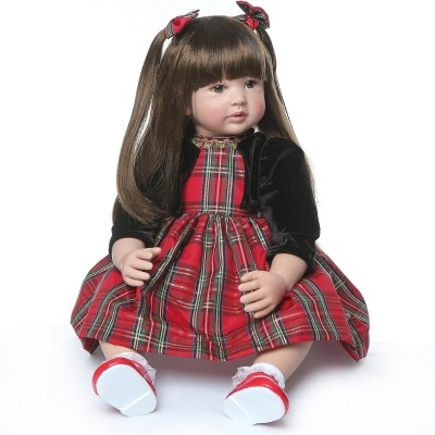 Boneca realista com vestido xadrez e casaco preto sentada.