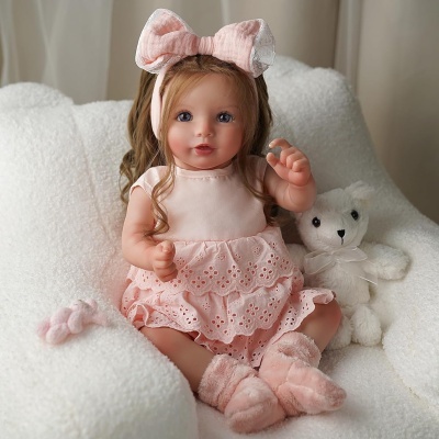 Boneca realista com vestido e laço rosa sentada no sofá com urso de peluche branco