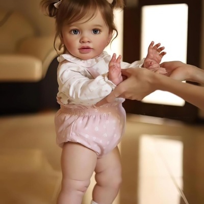 Bebé vestida de branco e rosa a ser ajudada a andar em piso interior refletor