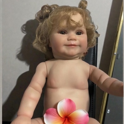 Boneca de bebé loira sem roupa sentada com flor colorida na zona abdominal