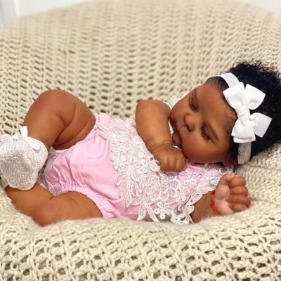 Boneca bebé vestida de rosa a dormir num puff de malha bege